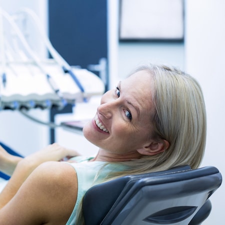 Woman laying on a dental treatment chair as she looks back at her dentist
